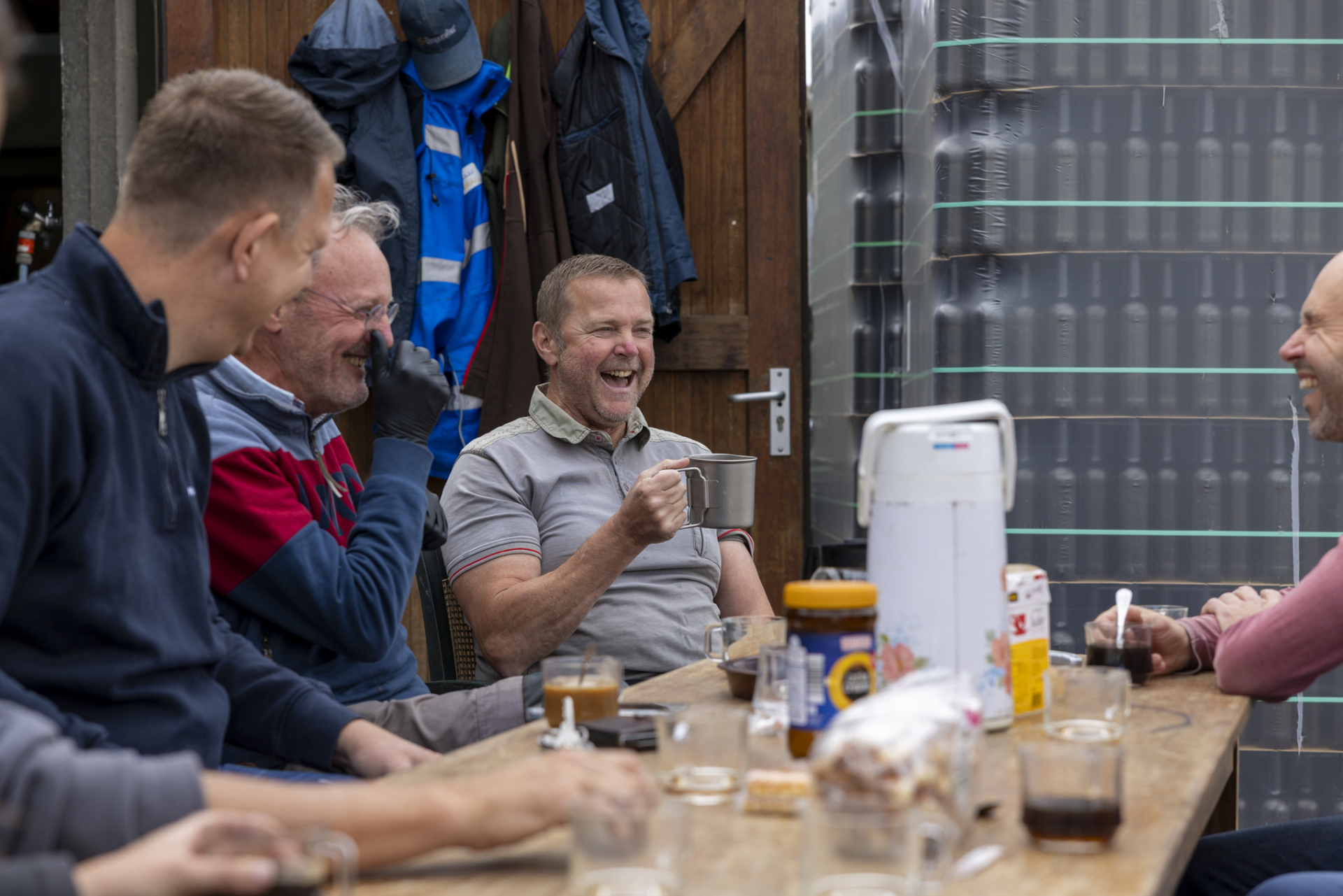 Medewerkers zitten gezellig aan tafel iets te drinken.